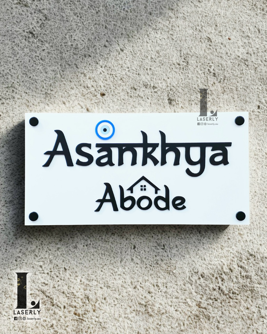 Acrylic house name sign in black and white featuring an evil eye motif, mounted on front wall.