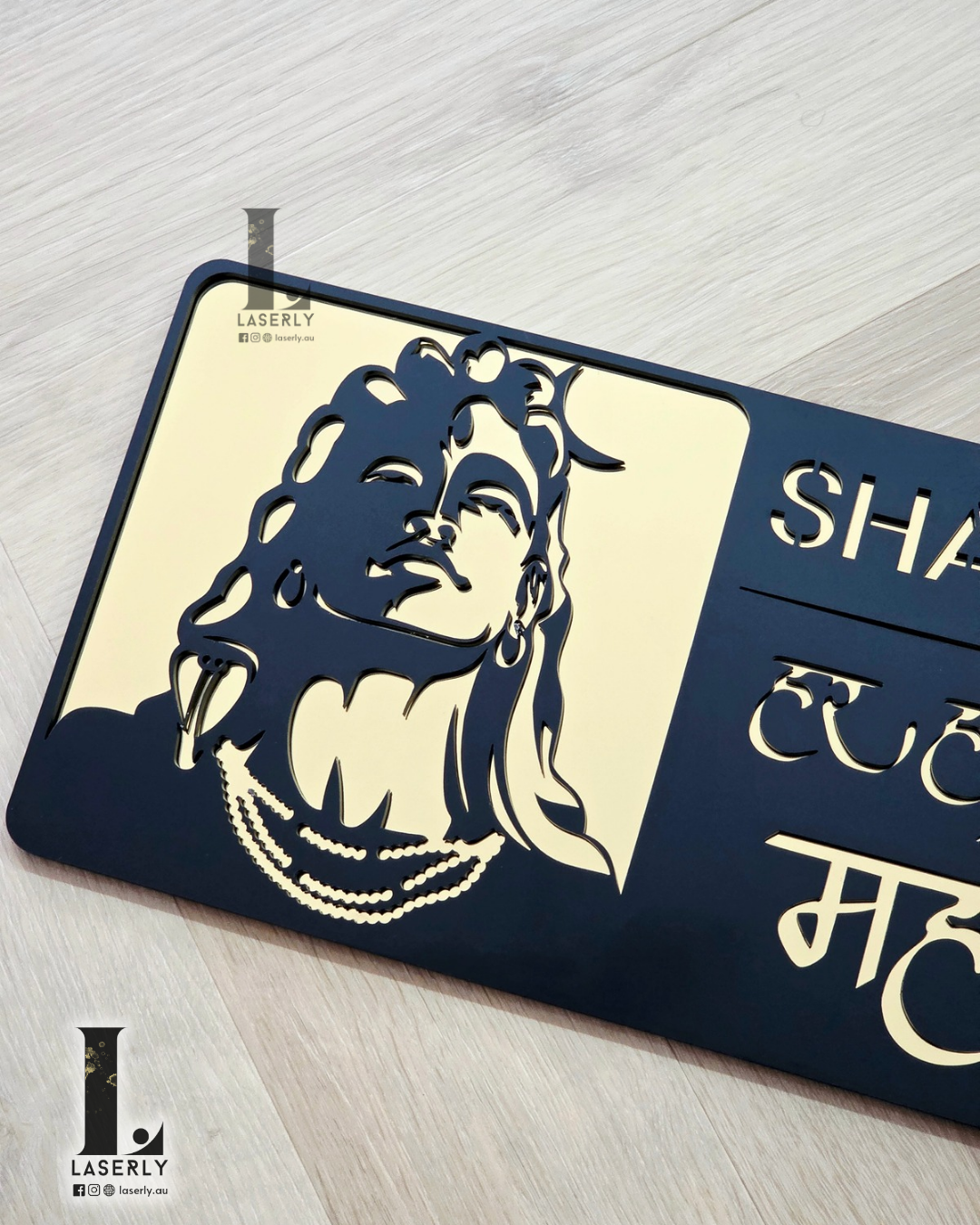 Acrylic gold and black Mahadev house number plaque with sleek mirror finish on exterior wall.