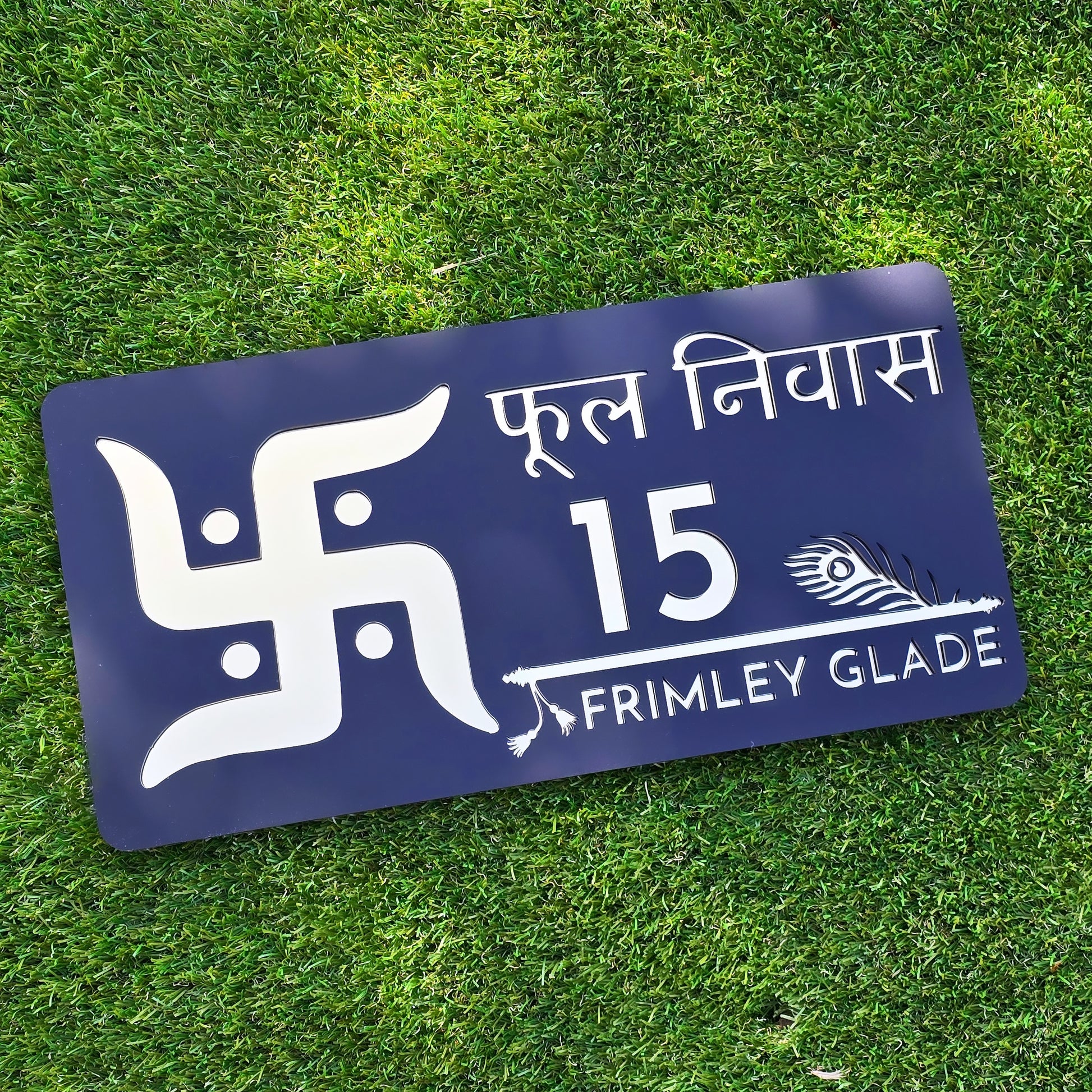 Modern black acrylic house number sign with mirror gold Swastika design mounted beside front door.