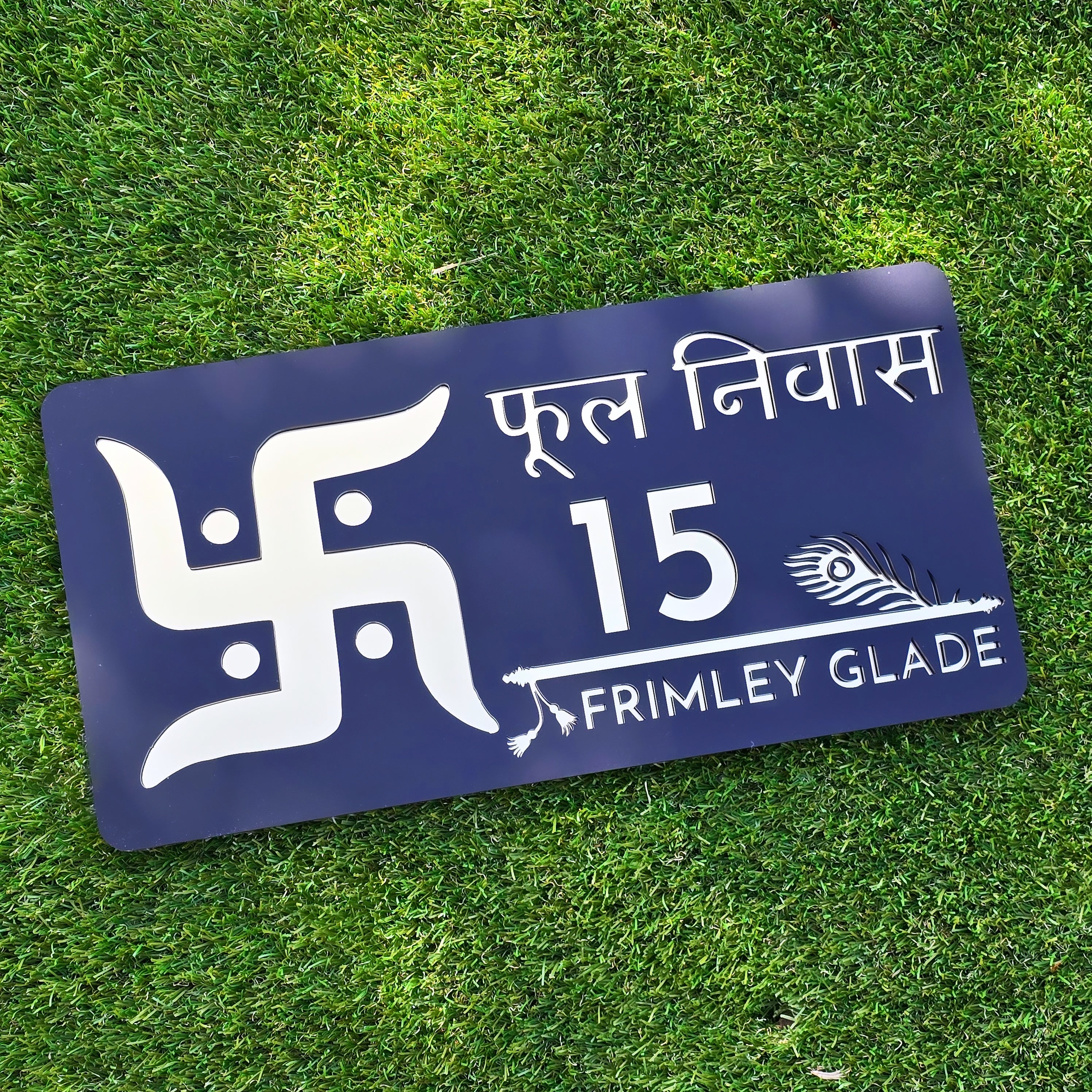 Modern black acrylic house number sign with mirror gold Swastika design mounted beside front door.