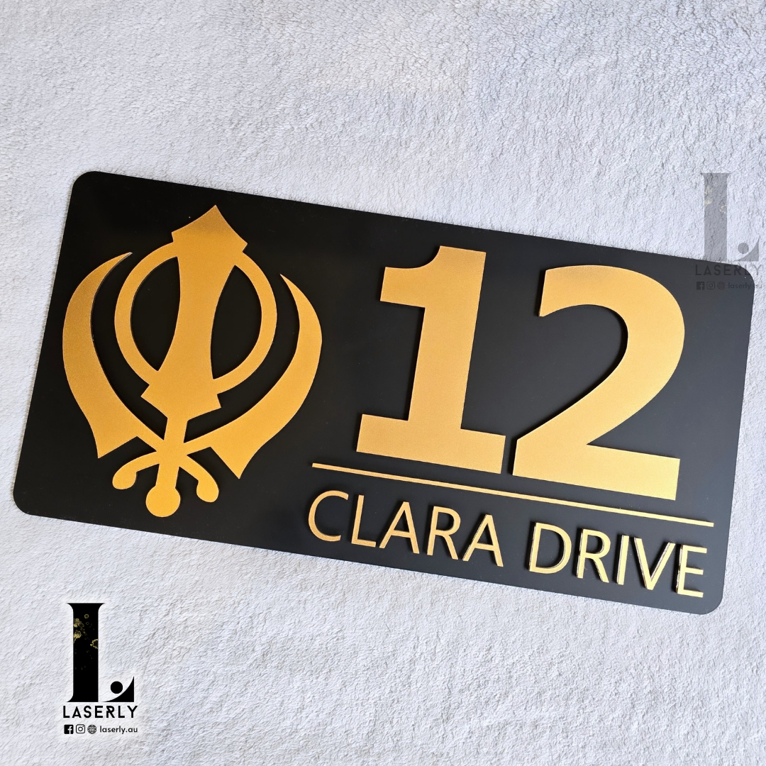 Black and metallic gold Kandha house number sign mounted beside modern front entrance.
