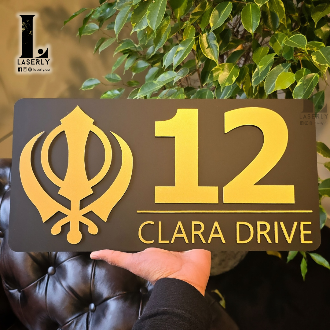 Luxury black and gold Kandha house number sign displayed on exterior wall.