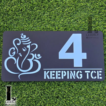 Black and silver mirror Ganesha house number sign mounted beside front door.