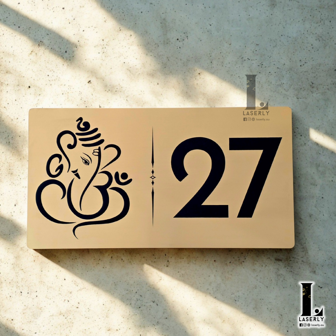 Brushed gold engraved Ganesha house number sign mounted on exterior wall beside the front door.
