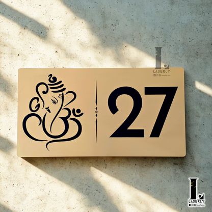 Brushed gold engraved Ganesha house number sign mounted on exterior wall beside the front door.