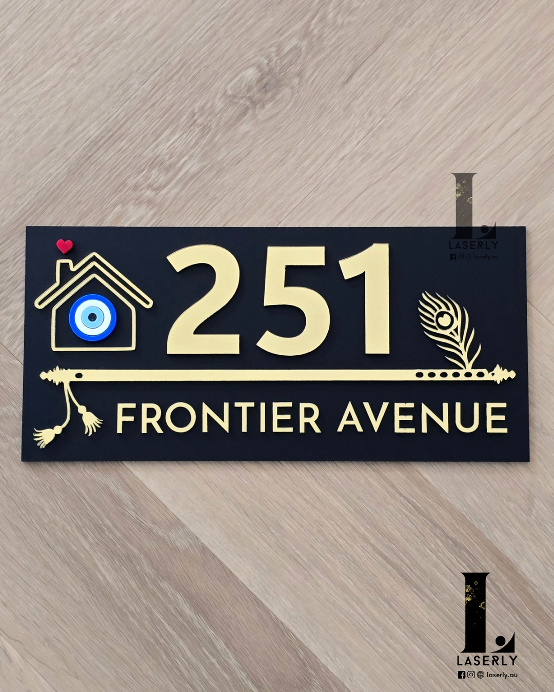 Black flute-themed house number sign featuring a protective evil eye design mounted on exterior wall.