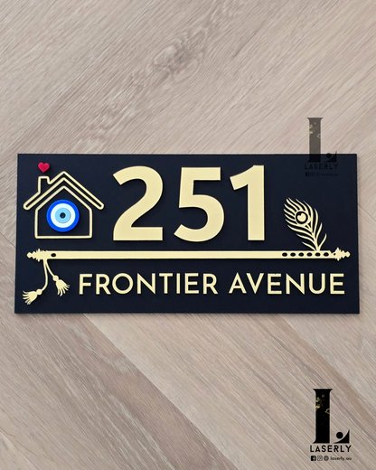 Black flute-themed house number sign featuring a protective evil eye design mounted on exterior wall.