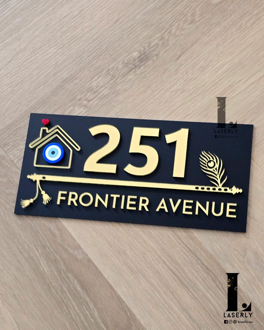 Laser-cut black acrylic house number sign with flute pattern and evil eye accent for home entrance.