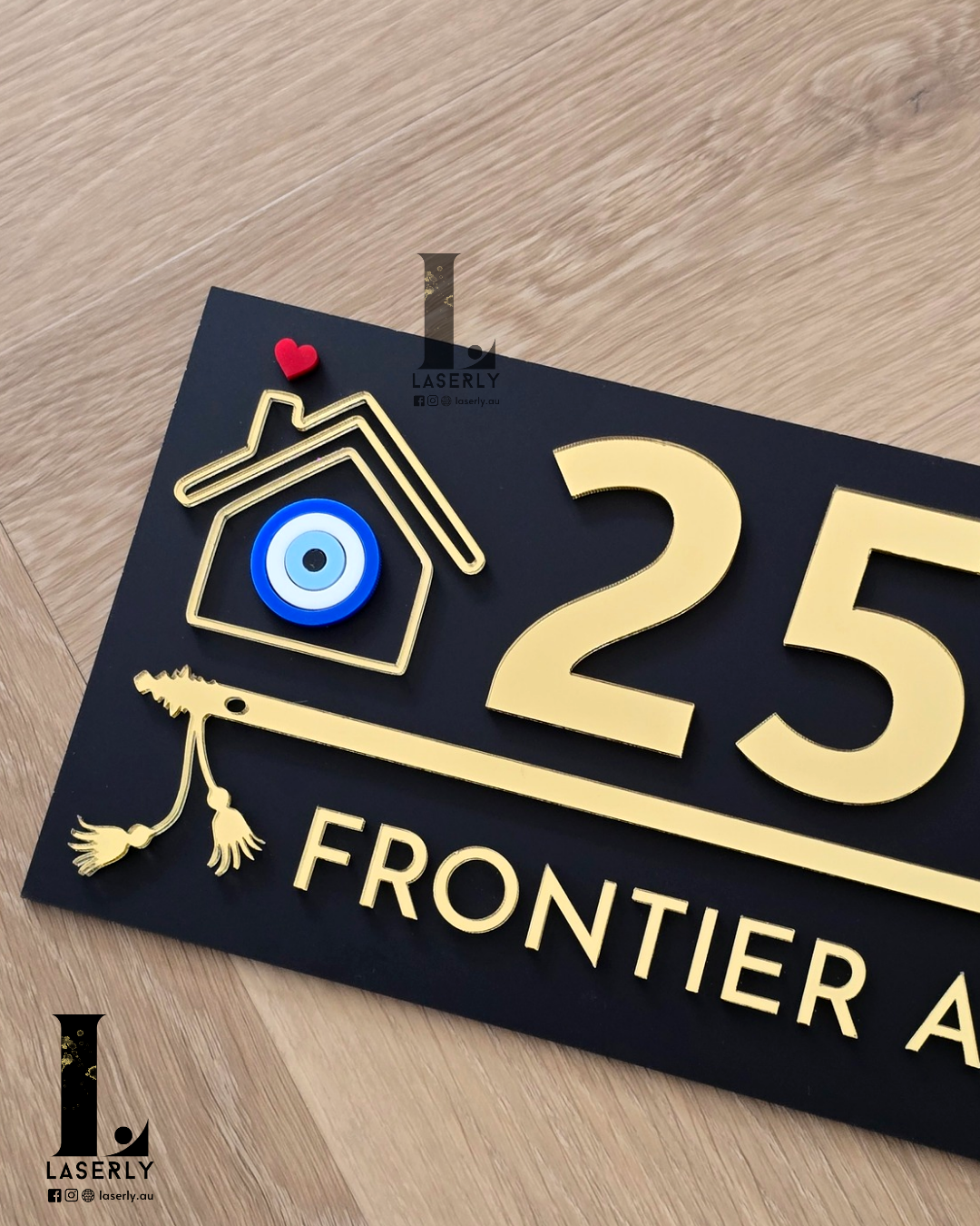 Decorative black exterior house number sign with flute artwork and evil eye protection symbol.