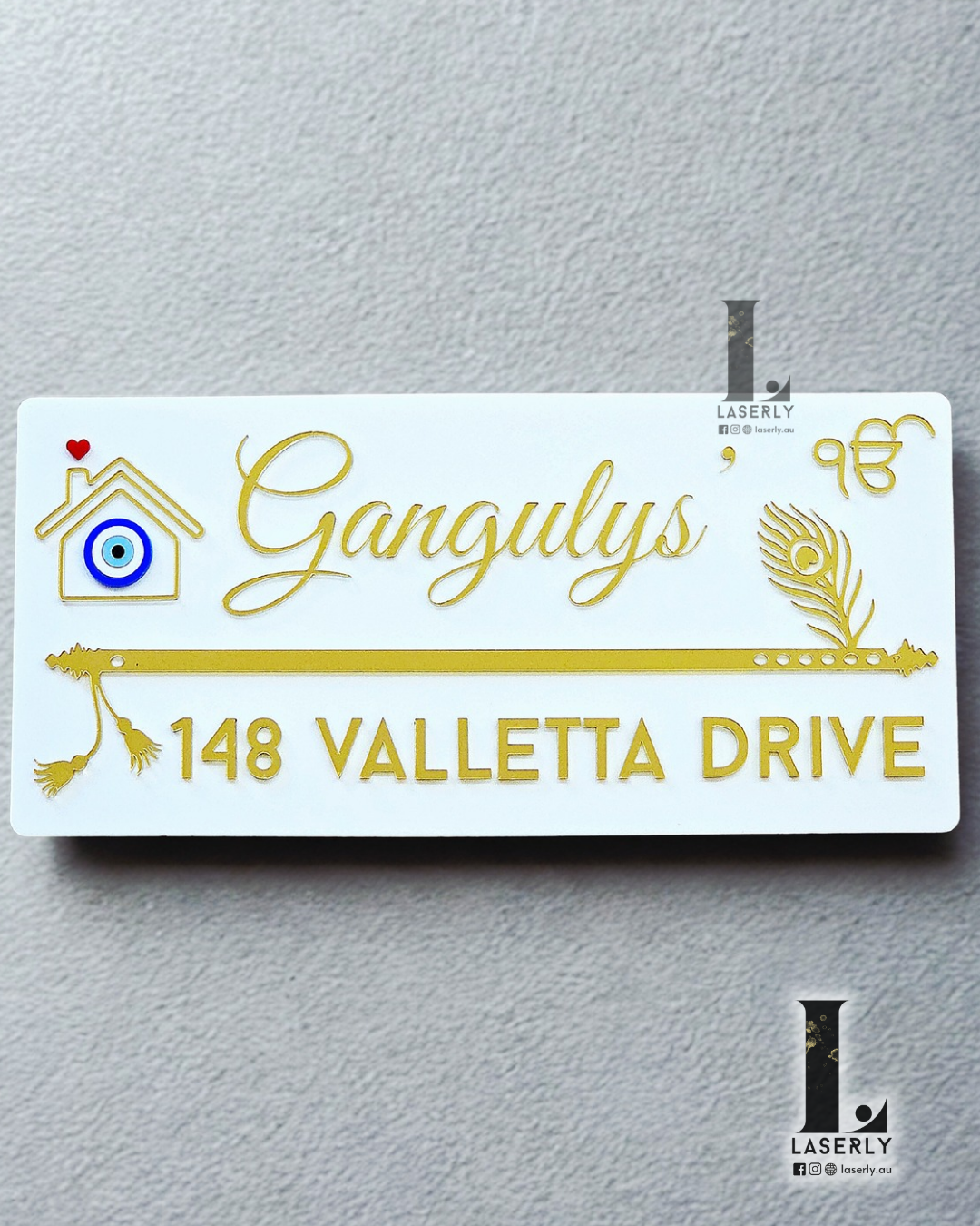 White flute-themed house number sign featuring a decorative evil eye symbol mounted on exterior wall.