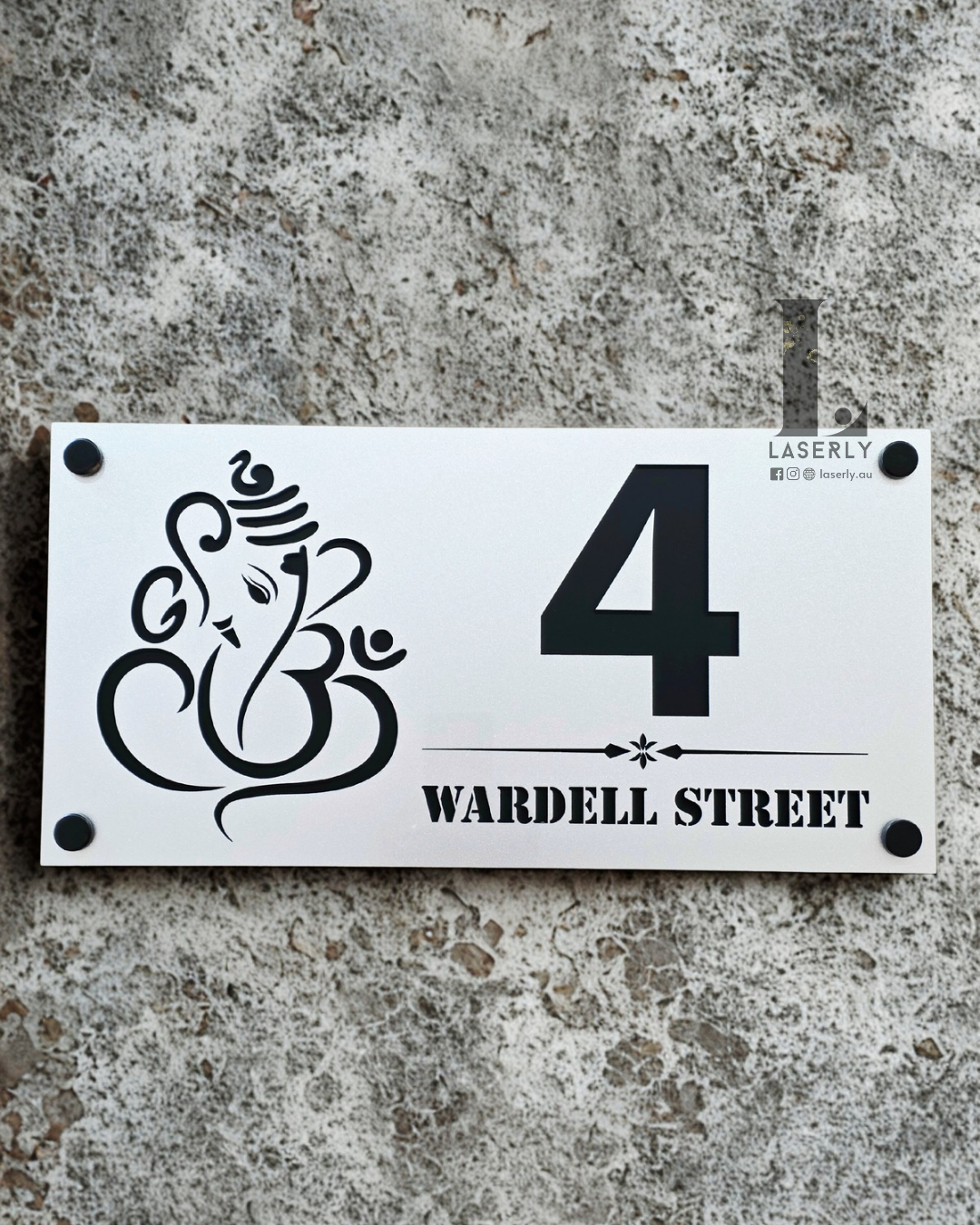 Laser-cut Ganesha acrylic house number plaque with metallic steel finish on exterior wall.