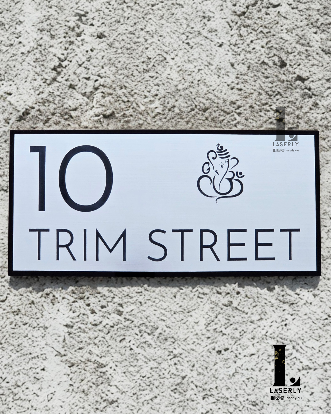 Sleek Ganesha-themed house number plate in minimalistic style beside front door.