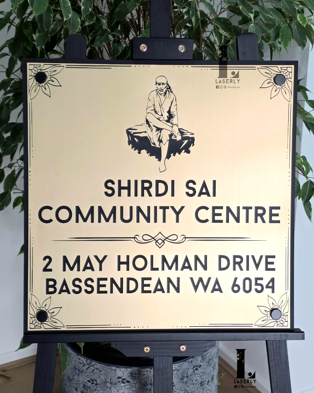Elegant Sai Baba house sign in gold and black acrylic on wall.