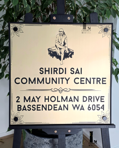 Elegant Sai Baba house sign in gold and black acrylic on wall.