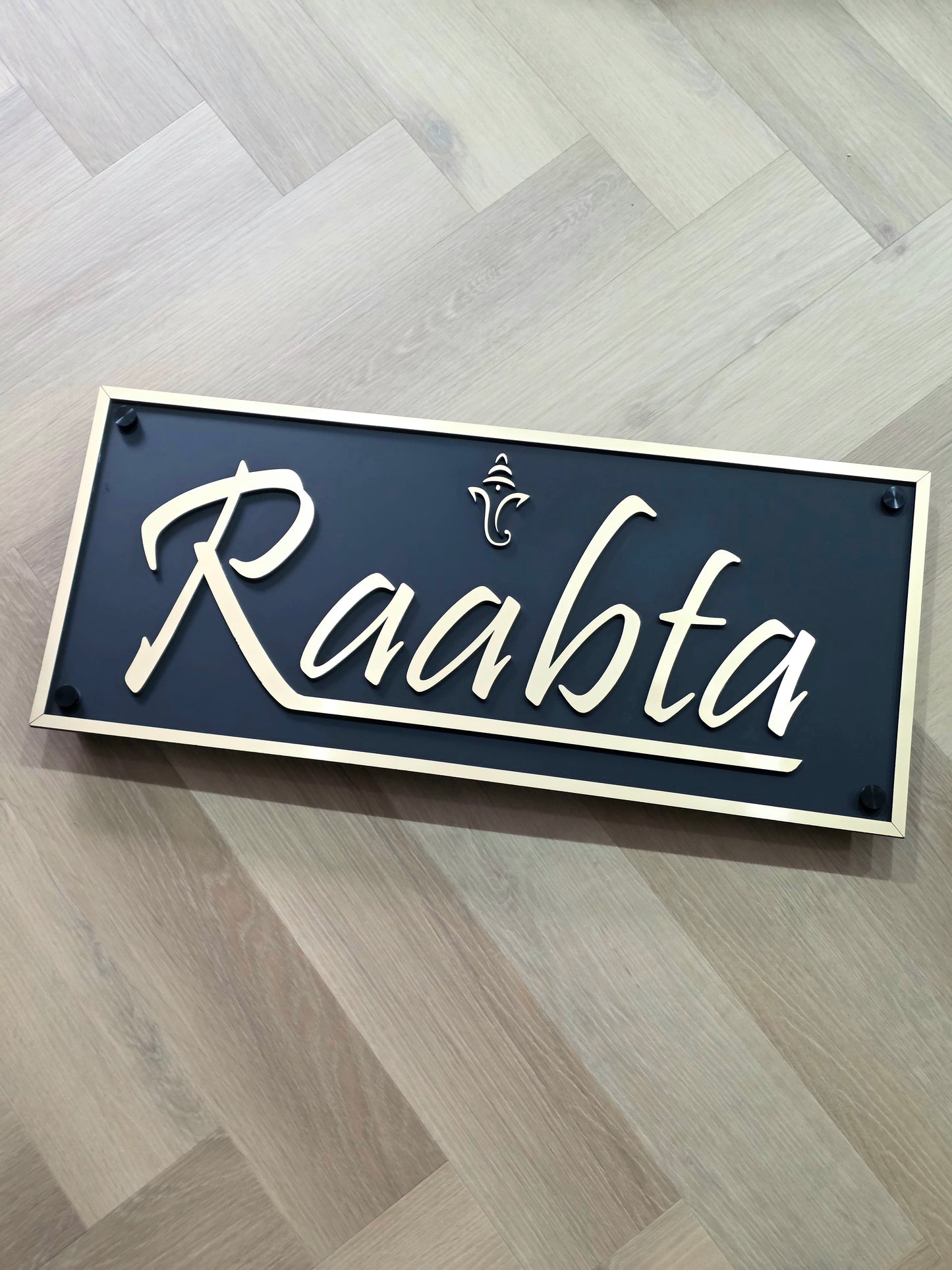 Modern Ganesha house number sign in gold and matte black acrylic installed next to main doorway.