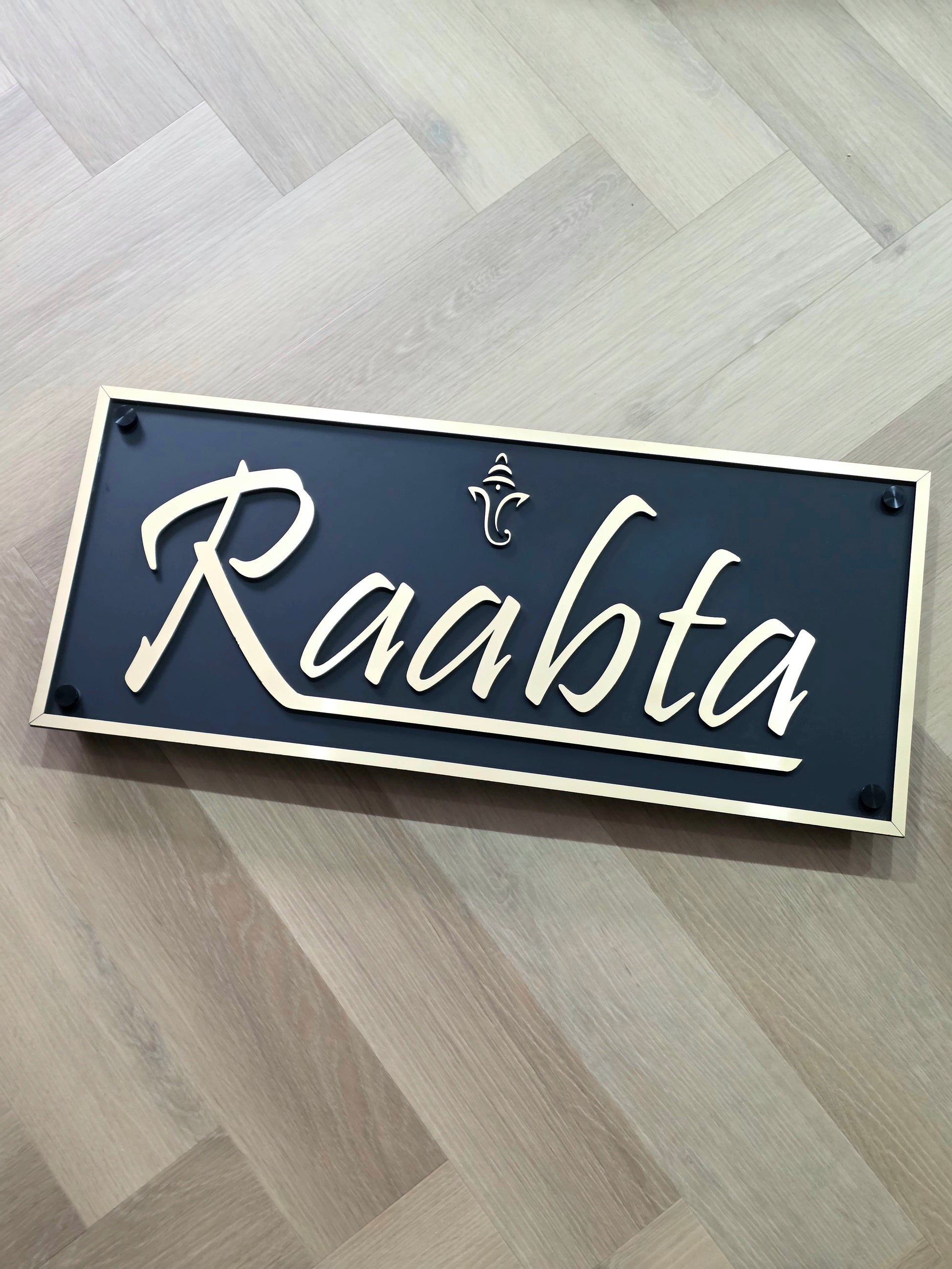 Modern Ganesha house number sign in gold and matte black acrylic installed next to main doorway.
