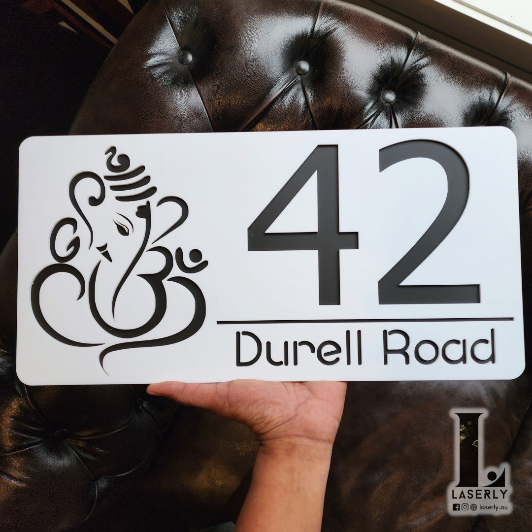 Front view of a matte black and white Ganesha house number sign mounted on exterior wall.