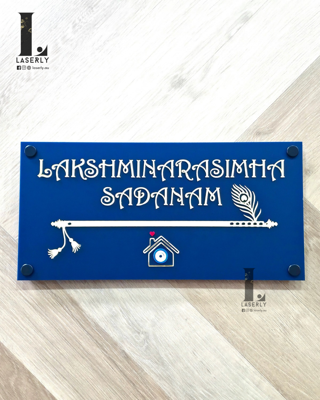 Navy blue house number sign featuring a flute design and evil eye detail mounted on a wall.