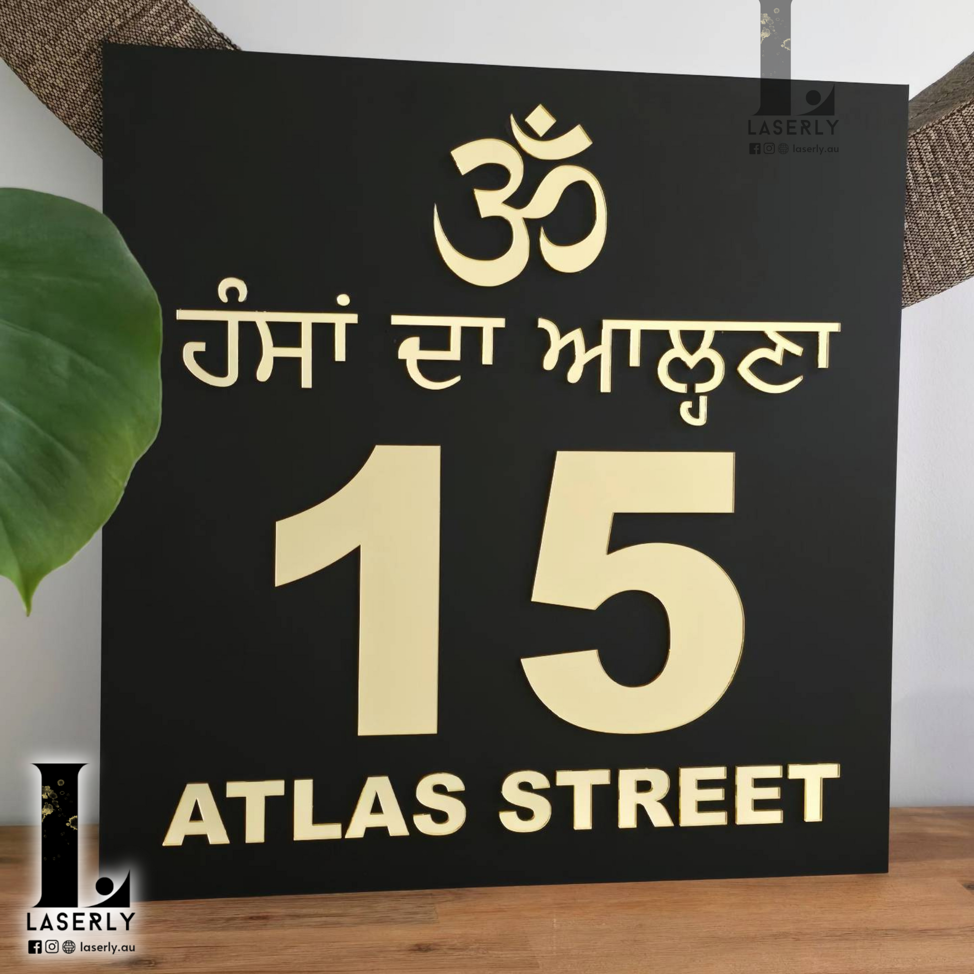 Close-up of a laser-cut OM Punjabi house number sign mounted beside a front door.