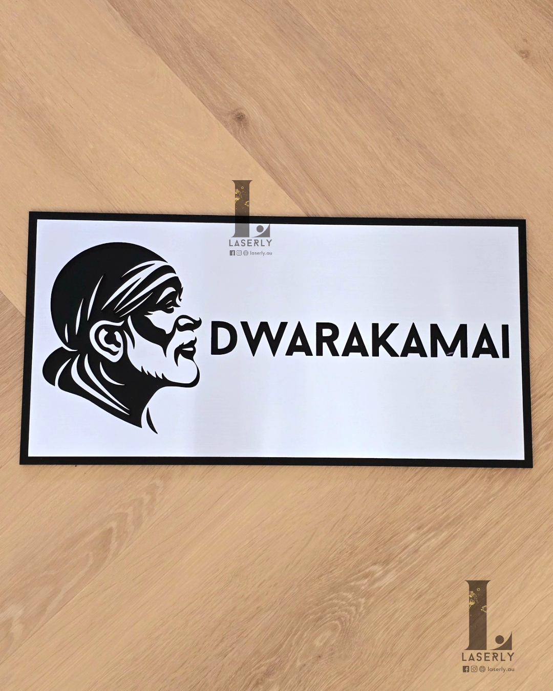 Silver and black Saibaba house number sign mounted beside the front door on an exterior wall.